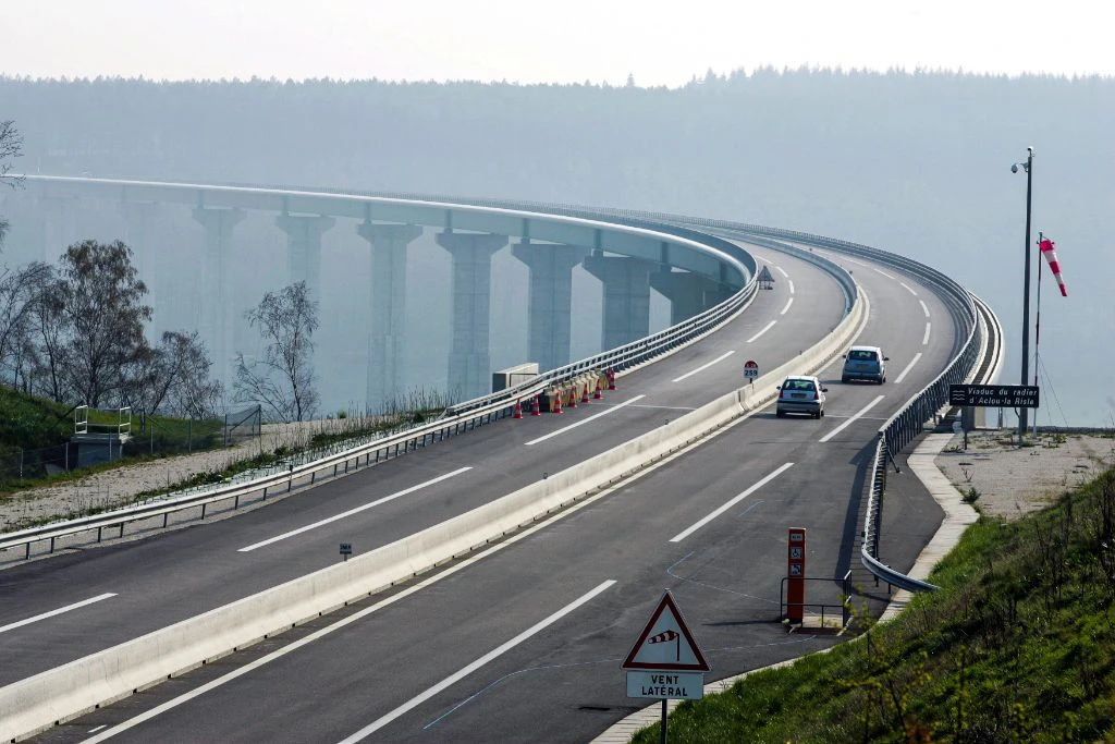 Autoroute en courbe avec viaduc brumeux en arrière-plan
